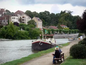 Dole - Ródano-Rhin canal con barcazas amarradas, la orilla decorada con un banco, de construcción, casas y árboles en la ciudad