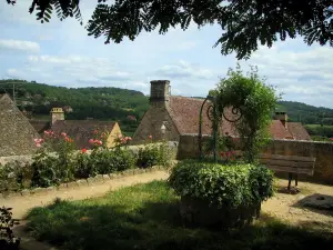 Domme - Jardín (así, el banco y rosas) con vistas a los tejados de la ciudad amurallada en el valle de la Dordogne, en Périgord