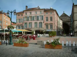 Épinal - Place des Vosges, con piante, fiori, fontane, caffetterie, portici e case nella Basilica di San Maurizio in background