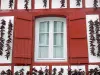 Espelette - Facciata di una casa con le persiane rosse decorato con ghirlande di peperoni