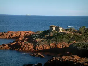 Estérel massif - Red rocks (porphyry) of the wild coast (côte sauvage), maquis (dense Mediterranean shrubland) and house with a view of the Mediterranean Sea and boats