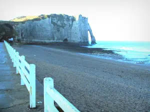 Étretat - Walkway of the seaside resort, pebble beach, the Aval cliff (chalk cliff) with its arc (the Aval gateway), and the Channel (sea)
