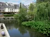 Évreux - Walk along the banks of River Iton, trees along the water, and buildings of the town