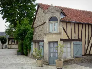 Exmes - Maison du village avec sa porte d'entrée bordée d'arbustes en pots