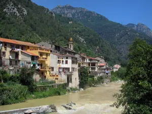 Fontan - Torre e case del villaggio da parte del fiume Roya e le montagne nella valle del Roya