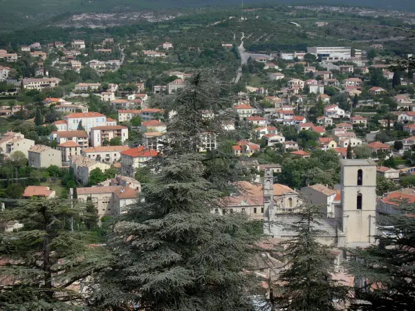 Forcalquier - View of the city: tower of the Notre-Dame-du-Bourguet cathedral, houses, buildings and trees in foreground