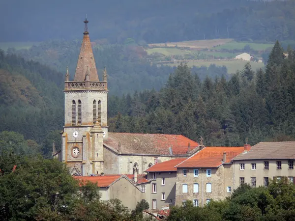 Forez mountains - Church bell tower and houses of the village of Saint-Anthème surrounded by pine trees and trees; in the Livradois-Forez Regional Nature Park