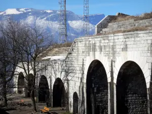 Fort de la Bastille - Site de la Bastille (sur la commune de Grenoble) : casemates du fort, arbres, bancs et montagnes en arrière-plan