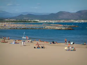 Fréjus - Fréjus-Plage: sandy beach with tourists, the Mediterranean Sea, cliffs, the Fréjus bay, and the hills in background