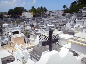 Friedhof von Morne-à-l'Eau - Grabstätten mit Schachbrettmuster schwarz-weiss, mit Blick auf die Fassaden der Häuser der Stadt