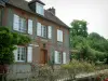 Gerberoy - Bakstenen huis met witte luiken en stenen, bomen en smeedijzeren hek met rozen (roze)