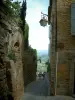 Gordes - Rue étroite en pente, maisons et collines au loin