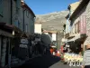 Gourdon - Street of the village lined with shops and restaurants with mountains in background