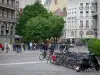 Grenoble - Alignement de vélos, arbres, tramway, commerces et façades de la ville
