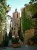 Grimaud - Empinada calle de la villa medieval, las casas de frente cubierto con plantas trepadoras y campanario de la Iglesia de San Miguel en el fondo