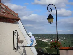 Hautvillers - Kunstgeschmiedetes Aushängeschild und Strassenlaterne geschmückt
mit Blumen mit Blick auf die Rebstöcke des Weinanbaus der Champagne, im Regionalen Naturpark der Montagne de Reims