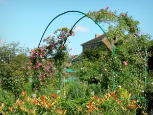 Huis en tuinen van Claude Monet - Monet's tuin in Giverny: Clos Normand: boog versierd met bloeiende rozen, lelies en oranje