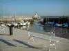 Île de Ré - La Flotte : quai et banc en premier plan avec vue sur les bateaux à marée basse et le phare du port