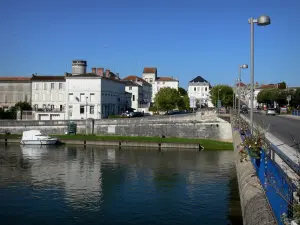 Jarnac - Puente adornado con farolas, barco de río Charente en el agua y las casas en la ciudad