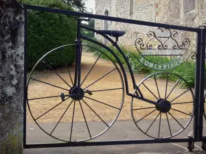 Kapel Notre-Dame-des-Cyclistes - Detail van de smeedijzeren poort van de Notre-Dame-des-Fietsers neerkomt op een oude fiets