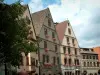 Kaysersberg - Maisons hautes aux façades ornées d'enseignes et aux fenêtres décorées de fleurs (géraniums)