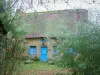 Kerhinet - House with a thatched roof (thatched cottage) and blue shutters, and trees in the Brière Regional Nature Park