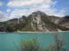 Lac de Castillon - Retenue d'eau couleur émeraude, arbres, rive et montagnes ; nuages dans le ciel bleu ; dans le Parc Naturel Régional du Verdon