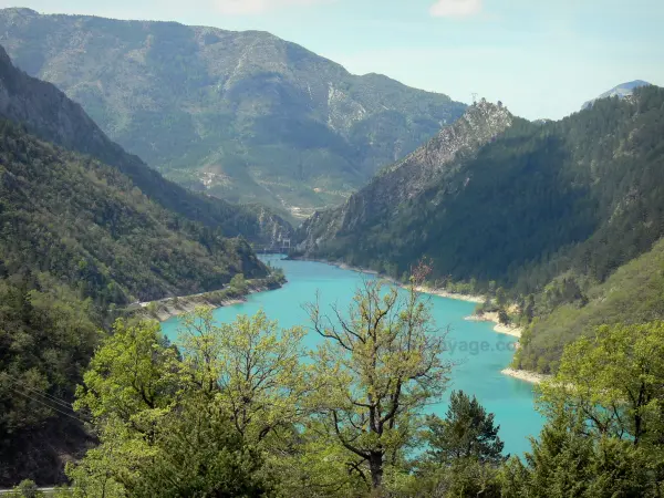 Lago di Chaudanne - Gli alberi in primo piano si affaccia sulla riserva d'acqua color smeraldo, circondata da montagne nel Parco Naturale Regionale del Verdon