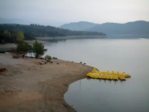 Lago de Saint-Cassien - Playa, árboles, barca a pedales amarillo amarrado a un pontón, lago, costa y las colinas boscosas