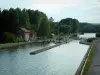 Landscapes of Picardy - Side canal of the Oise river with a lock, moored barges, banks and trees of a forest