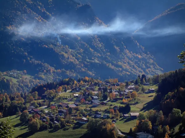 Landscapes of the Savoie in automn - Houses of a village, trees in autumn and mountains covered with forests
