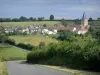 Landschaften der Bourgogne - Dorf Sémelay, mit seinen Häusern und seinem Glockenturm der Kirche Saint-Pierre, und Strasse gesäumt von Wiesen