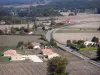 Landschaften des Lot-et-Garonne - Strasse gesäumt von Ackerland, Häusern und Bäumen