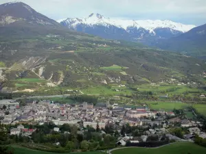 Landschappen van de Hautes-Alpes - Durance vallei: uitzicht over de daken van de oude stad van Embrun, de Durance rivier omzoomd met bomen, weiden en met sneeuw bedekte bergen