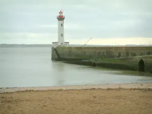 Landschappen van de kust van de Loire-Atlantique - Sandy strand en de vuurtoren van Oude Mol, in Saint-Nazaire, de zee (Atlantische Oceaan) kust op de achtergrond en bewolkte hemel