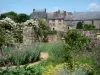 Lassay-les-Châteaux - Floración de jardín medieval, Notre-Dame-du-Rocher y casas de la ciudad en el fondo
