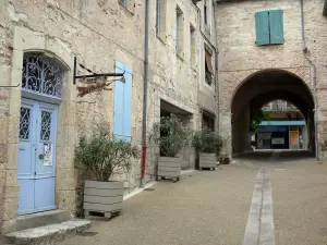 Lauzerte - Archway, arbustos en maceta y las fachadas de las casas en el pueblo (casa de pueblo medieval)