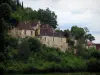 Limeuil - Houses of the medieval village, trees and cloudy sky, in Périgord