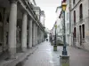 Lons-le-Saunier - Colonne rotonde con teatro di strada, lampioni, negozi e facciate di case