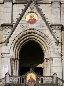 Lourdes - Gebiet der Grotte (Heiligtümer, religiöse Stätte): Fassade der Basilika Immaculée Conception (Obere Basilika) im neugotischen Baustil mit dem Mosaik-Medaillon darstellend Pius X (unten) und dem Medaillon darstellend Pius IX (oben)