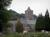 Lucerne abbey - Bell tower of the abbey church dominating the convent buildings, Normandy cows in a meadow and trees