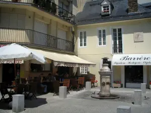 Luchon - Pequeña plaza con una fuente, restaurante con terraza, tienda y casas del balneario