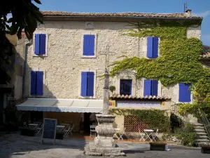 Lussan - Casa in pietra con le persiane blu, terrazza del ristorante e del Calvario