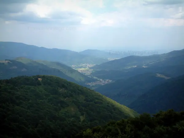 Massiv der Vogesen - Berge bedeckt mit Wäldern (Regionaler Naturpark der Ballons des Vosges), Dörfer und Wolken im Himmel