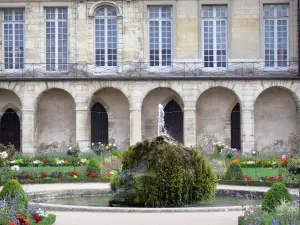 Meaux - Facade of the former bishop's palace and Bossuet garden (French-style formal garden of the former bishop's palace), rock of the pond and flowerbeds