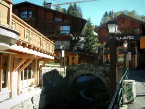 Megève - Lampadaires, petit pont en pierre enjambant le cours d'eau, boutiques et chalets du village (station de sports d'hiver et d'été)