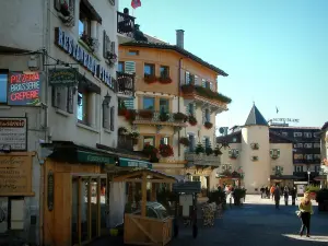 Megève - Rue piétonne du village (station de sports d'hiver et d'été) avec boutiques, terrasse de café et maisons aux fenêtres et aux balcons décorés de fleurs