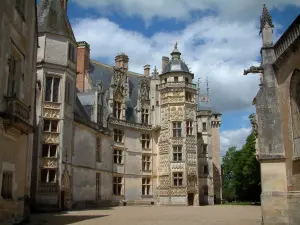 Meillant castle - Court, chapel and facade of the castle of Flamboyant Gothic style with its Lion tower, clouds in the blue sky