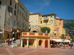 Menton - Tall houses in the colourful facades, but also columns and terrace of restaurant