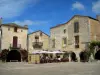 Monpazier - Houses with facades decorated with climbing roses, arches and café terrace of the Cornières square (central square of the fortified town), in Périgord